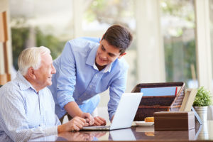Teenage Grandson Helping Grandfather With Laptop